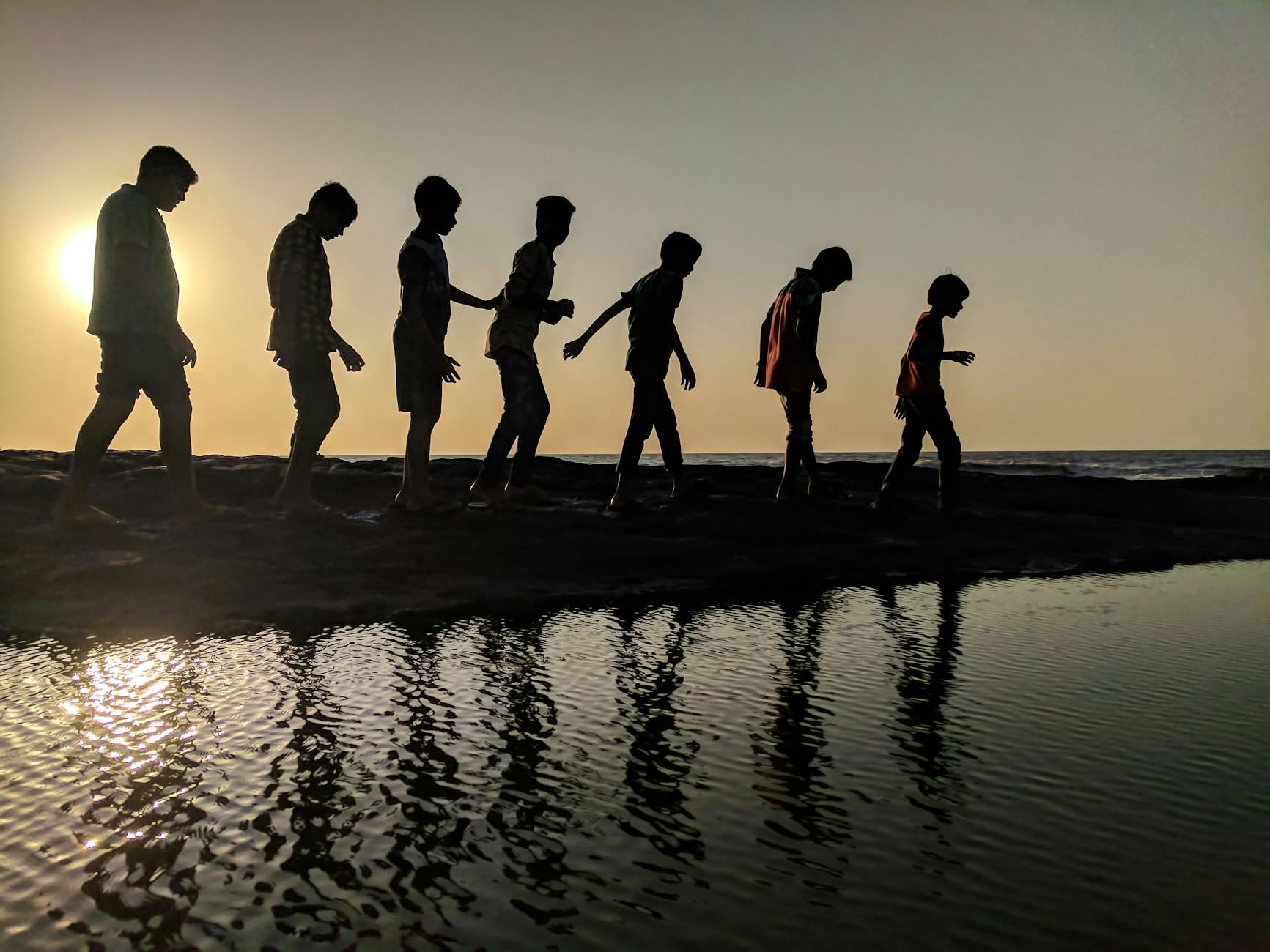 Como é o desenvolvimento do cérebro da criança até a fase adulta? group of children walking near body of water silhouette photography
